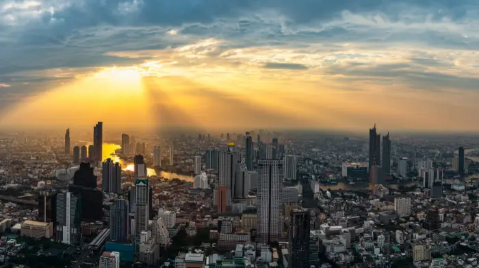 A golden Bangkok sunset spills over the skyline, as seen from one of the rooftop bars in Sukhumvit. This breathtaking cityscape, featured on The Road to Timbuktu, highlights why solo travellers over 50 flock to these sky-high spots for a memorable evening drink with a view.