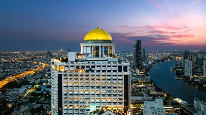 The golden dome of Lebua at State Tower glowing at dusk, overlooking the Chao Phraya River—an iconic spot for rooftop drinks Bangkok is famous for. Featured on The Road to Timbuktu, it’s a must-visit for mature solo travellers in search of skyline views and stylish sips above the chaos.