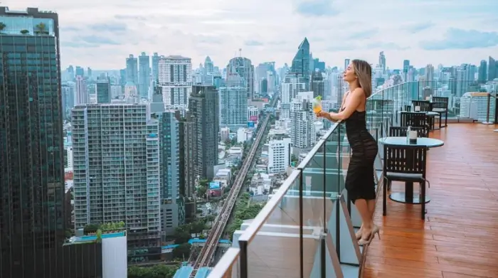 A woman enjoys a cocktail with sweeping skyline views from the Octave Rooftop Bar—an elevated escape that embodies mature nightlife Bangkok style. Featured on The Road to Timbuktu, it’s an ideal pick for solo travellers over 50 looking for quiet glamour above the city buzz.
