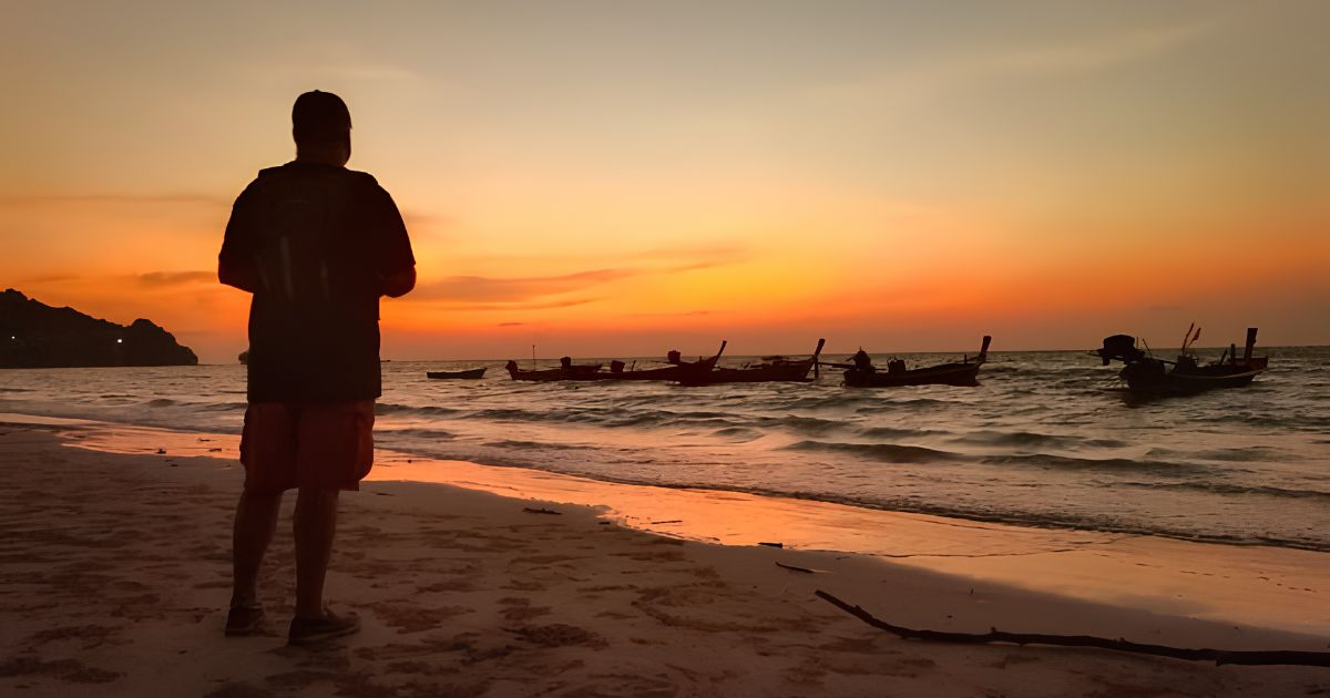 Zander Kane watching the sunset over Nai Yang Beach, Thailand, longtail boats on the horizon